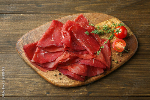 Tasty bresaola, peppercorns, tomatoes and thyme on wooden table, top view