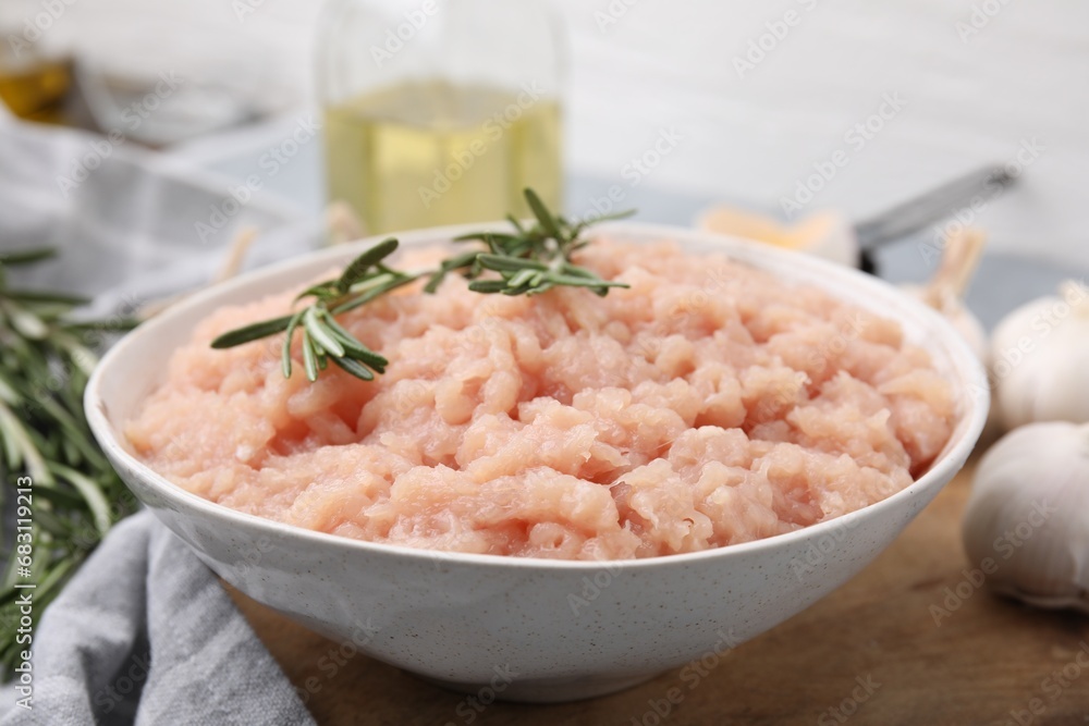 Fresh raw minced meat and rosemary in bowl on table, closeup Fresh raw minced meat and rosemary in bowl on table, closeup