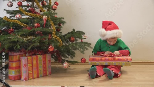 Wallpaper Mural Kid with elf costume trying to open his present near Christmas tree Torontodigital.ca