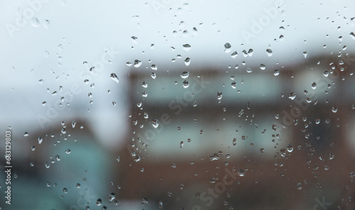 Raindrops adorn windowpane, creating a melancholic ambiance, symbolizing solitude, introspection, and nature's serene beauty on a rainy day