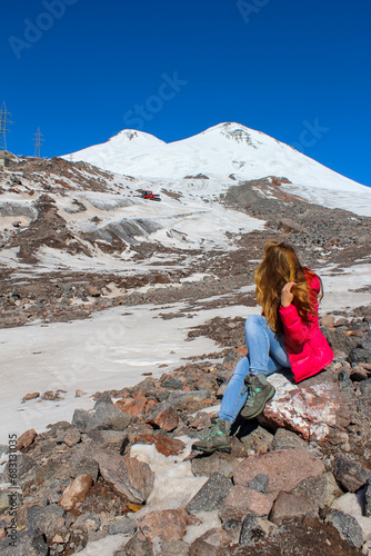 Girl sitting on the rock overlooking Elbrus mountain, Russia