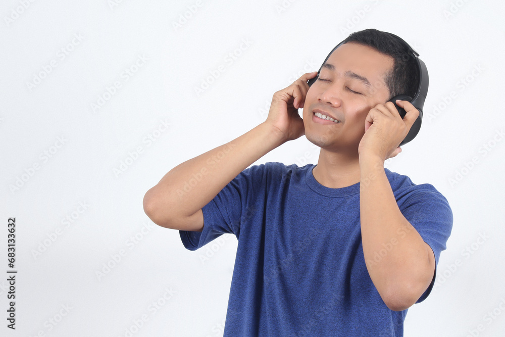 Enjoy The Sound. Portrait Of Joyful Asian Guy Wearing Wireless Headset Listening To Favorite Music Or Song With Closed Eyes Enjoy The Sound. Portrait Of Joyful Asian Guy Wearing Wireless Headset Listening To Favorite Music Or Song With Closed Eyes