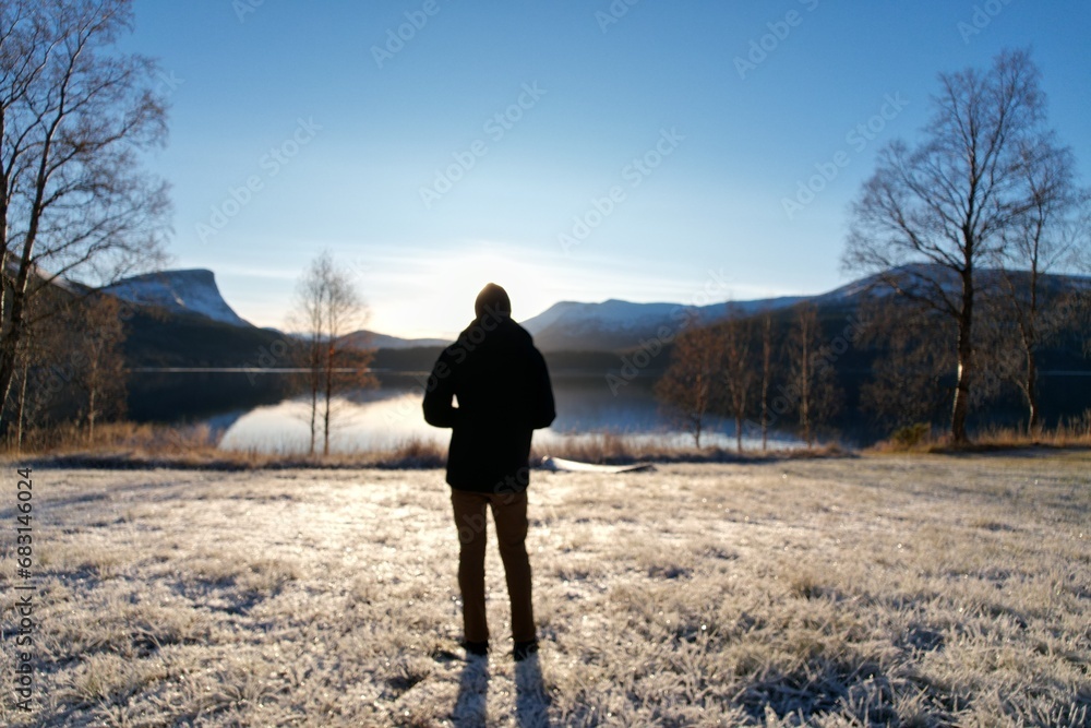 A man stands in contemplation as the Norway sunrise embraces the frosty landscape