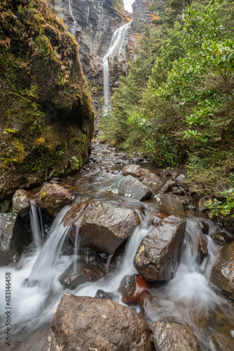 Fast flowing, rocky, mountain stream with the Waitonga Falls in the background. On the flanks of Mount Ruapehu, Tongariro National Park, New Zealand.
