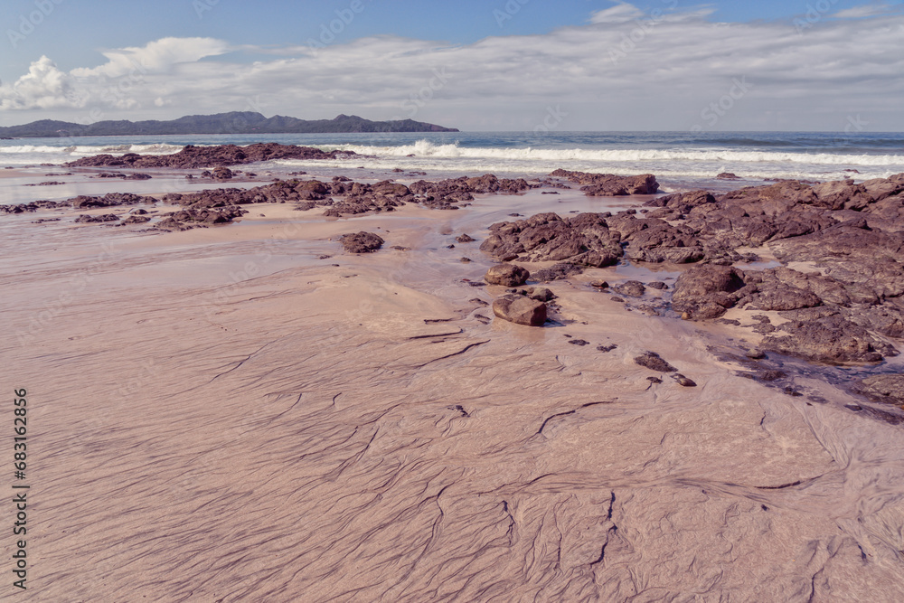 Landscape of a textured rocky beach with the ocean and hills in the distance Landscape of a textured rocky beach with the ocean and hills in the distance