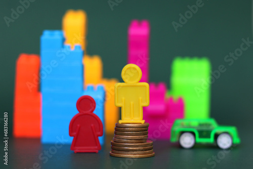 composicao feita com brinquedos plásticos, simbolizando a desigualdade de genero, com figura masculina sobre pilha de moedas em meio a cidade. photo