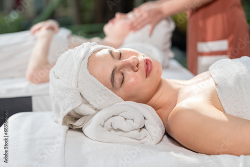 Relaxed young woman lying on massage table with eyes closed in spa salon