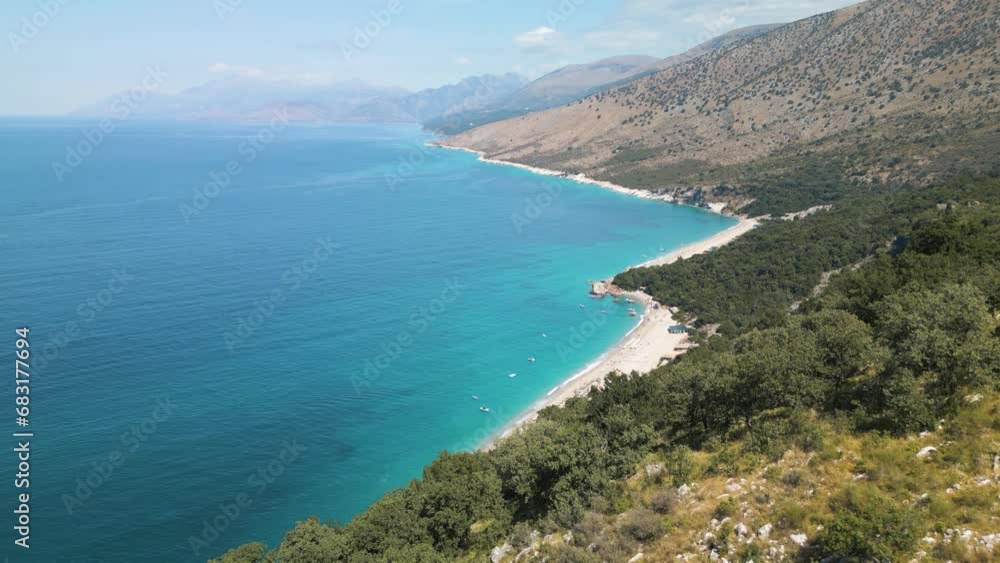 Drone dolly push past rugged hillside to reveal tropical white sand party beach Drone dolly push past rugged hillside to reveal tropical white sand party beach