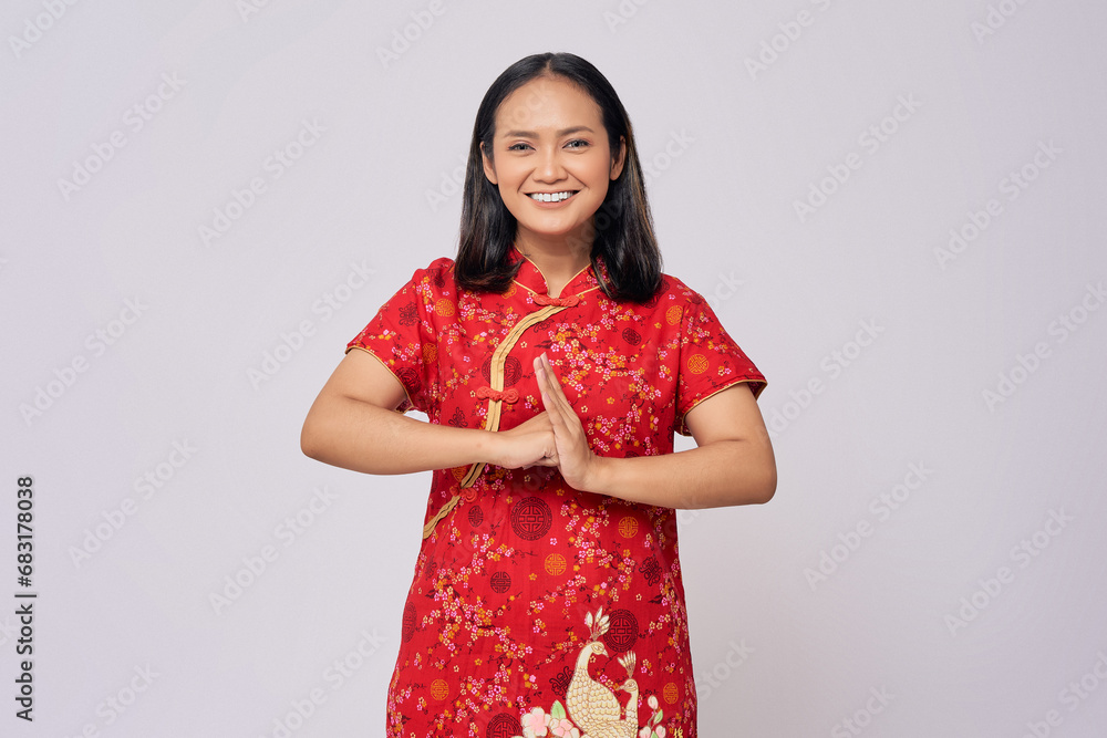 Happy Chinese New Year. Young Asian woman wearing traditional cheongsam qipao dress with gesture of congratulation isolated on white background Happy Chinese New Year. Young Asian woman wearing traditional cheongsam qipao dress with gesture of congratulation isolated on white background