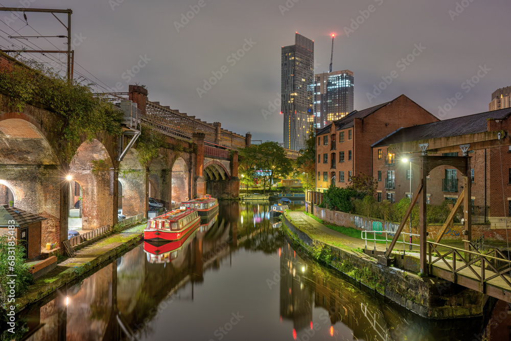 Castlefield in Manchester, UK, at night, with a modern skyscraper in the back