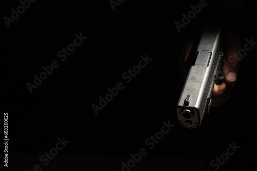 Close-up of a man's hand holding a small pistol ready to shoot in the dark, scary black background.defense or attack murderer or armed robber, First person view of a pistol.