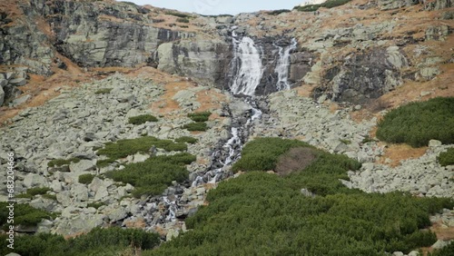 Water falls in slow motion spreading across rocks draining into green shrub and shale in Sliezsky Dom, High Tatras Slovakia photo