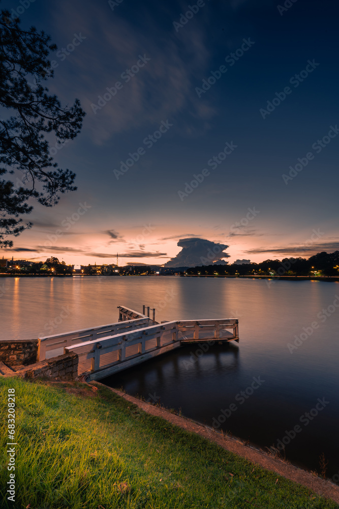 Sunset view on Xuan Huong lake, far away is Da Lat City with development buildings, transportation, market. Tourist city with center square of Da Lat city.