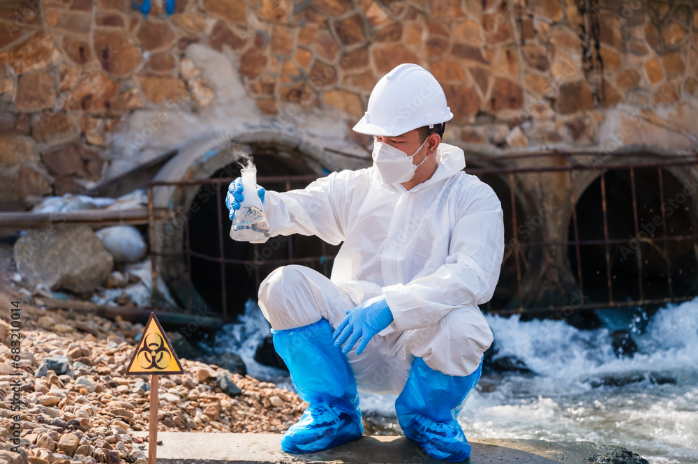 Ecologist man examines wastewater with pH test results discharged from sewers of refineries into nature to prevent chemical contamination and biohazard.