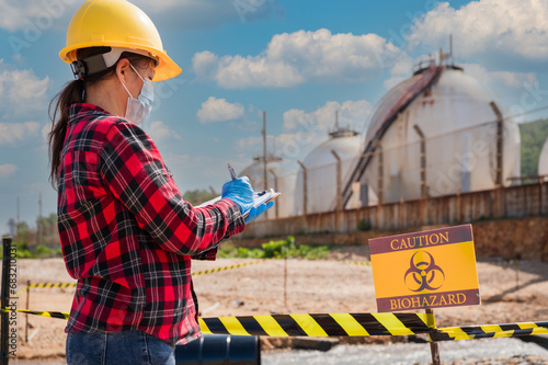 Female petrochemical engineer worker checks the gas storage industry and oil refinery plant industry for quality control and natural environment to prevent biohazards.