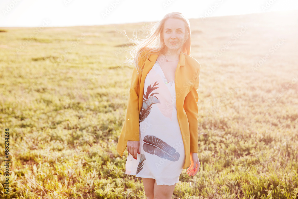 blonde woman walking through a green field at sunset blonde woman walking through a green field at sunset