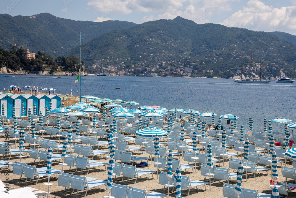 Umbrellas blue and seats in a private beach aside changing room wooden hut in italy coast