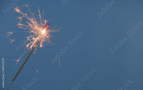 Christmas sparkler burning on blue background  copy space for text.