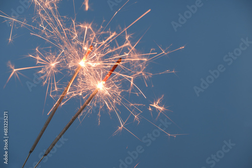 Two firework sparklers burning on blue background photo