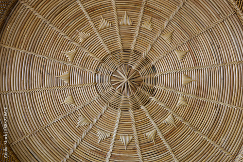 Circular woven rattan. Close up of a beautiful hand-woven patterned wicker basket. Brown rattan texture and background. Selective focus