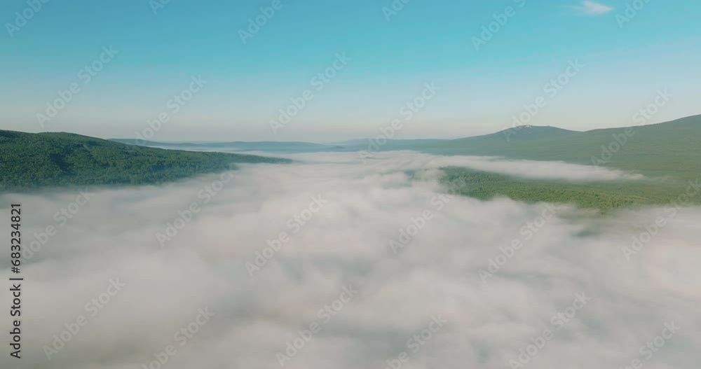 Flying over the fog under the river and forest and blue sky over the top of the inversion cloud level on a bright sunny day. Aerial drone wide view at summer sunrise Flying over the fog under the river and forest and blue sky over the top of the inversion cloud level on a bright sunny day. Aerial drone wide view at summer sunrise