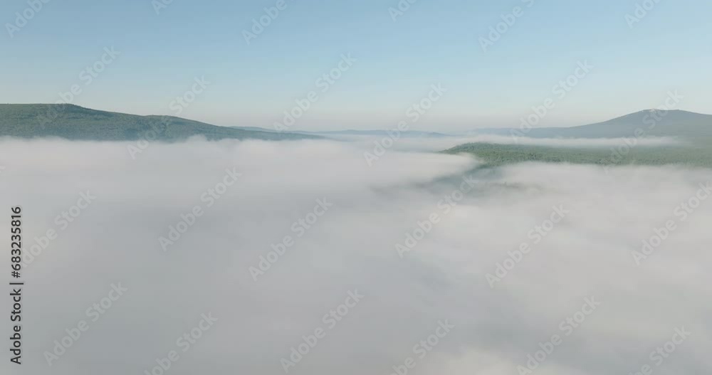 Flying over the fog under the river and forest and blue sky over the top of the inversion cloud level on a bright sunny day. Aerial drone wide view at summer sunrise Flying over the fog under the river and forest and blue sky over the top of the inversion cloud level on a bright sunny day. Aerial drone wide view at summer sunrise