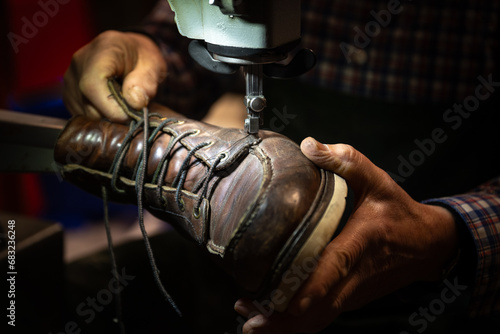Schuster, der einen alten Schuh in den Händen hält und an der Nähmaschine reparieren will photo