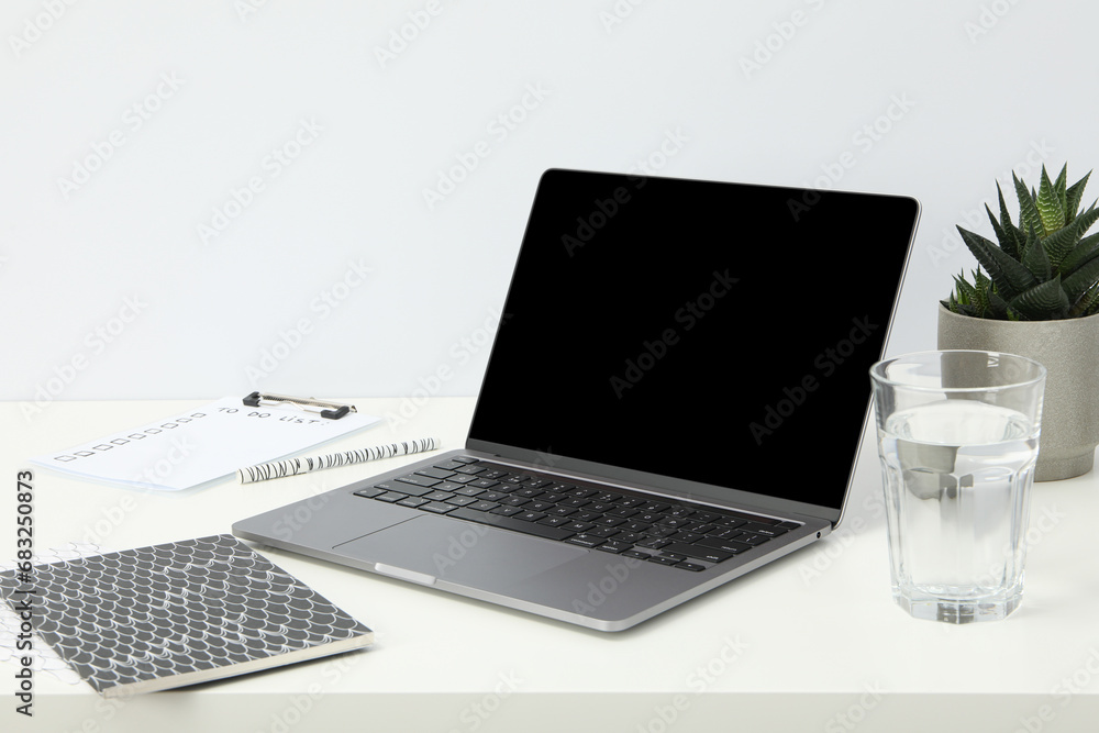 An open laptop with a glass of water and a flower pot An open laptop with a glass of water and a flower pot