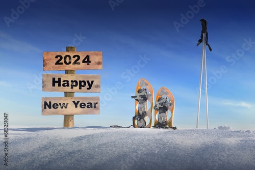 wooden sign with text happy new year in the snow next to snowshoes and ski sticks