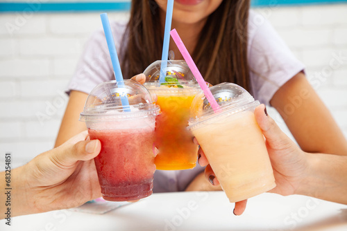 Friends holding drinking together fruity slush drinks. photo