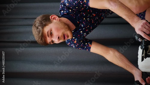 Portrait of young male athlete training on stationary bicycle. Vertical video