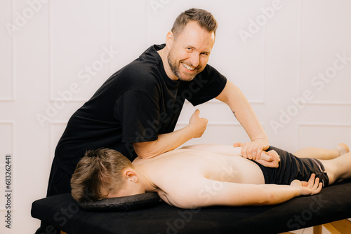 Man professional doctor osteopath fixing and stretching mans back with hands during exersicing at rehabilitation theapy in manual therapy clinic, top view. Chiropractor during work