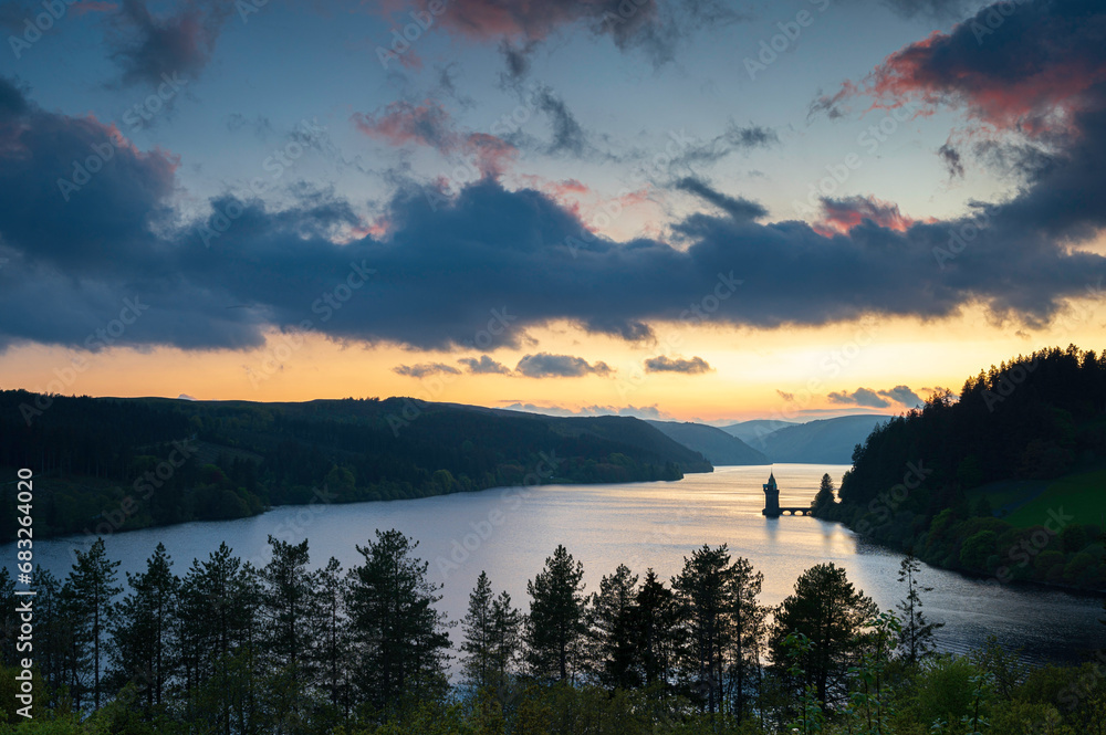 Lake Vyrnwy, located in mid Wales, an area of outstanding natural beauty, at sunset.  The orange sky is reflected in the calm water of the lake