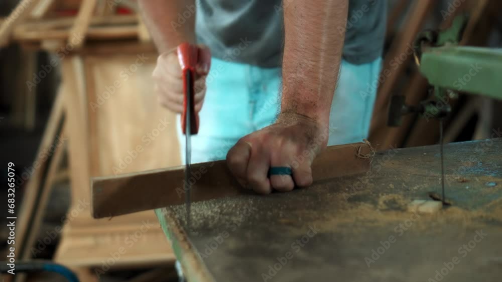 Man's hands working with wood in workshop, saw on wood Man's hands working with wood in workshop, saw on wood