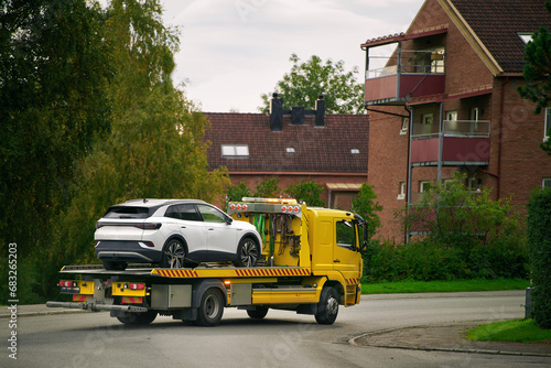 Fototapeta Naklejka Na Ścianę i Meble -  A car with a broken engine on the road, being towed by a truck to a repair shop, as part of the roadside assistance and vehicle recovery service.