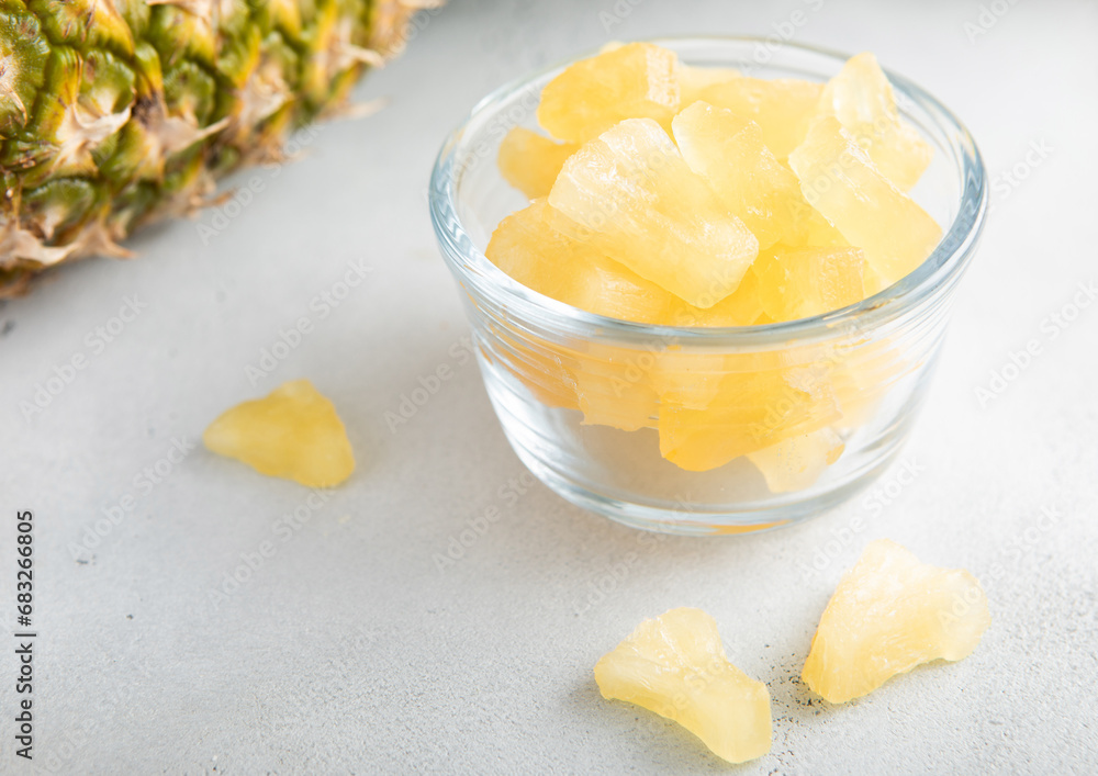 Dried soft sweet pineapple slices in glass bowl with raw pineapple on light table. Dried soft sweet pineapple slices in glass bowl with raw pineapple on light table.