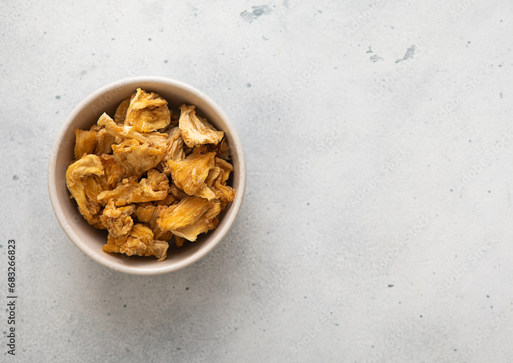 Dried pineapple slices chips in glass bowl on light background.Top view. Dried pineapple slices chips in glass bowl on light background.Top view.