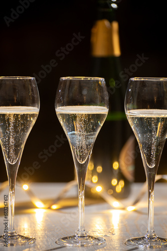 New year party, small bubbles of brut champagne cava or prosecco wine in tulip glasses with garland  lights on background photo