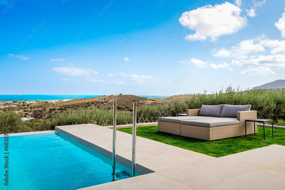 Summertime Oasis: A luxurious double sun bed positioned beside a sparkling pool, offering an idyllic retreat with a panoramic view of the sea and surrounding landscape. 