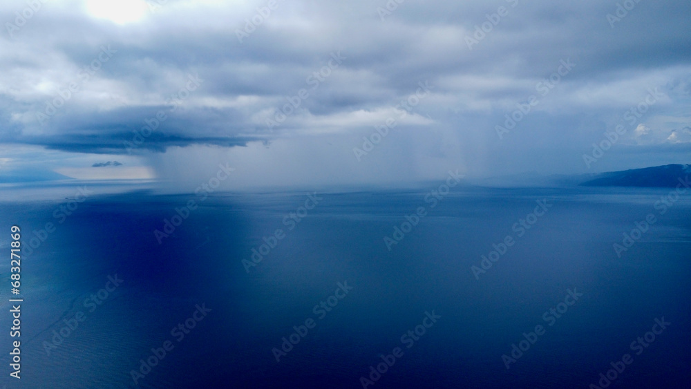 View from above of the rain in the distance. Aerial view of a rain cloud over the blue sea.