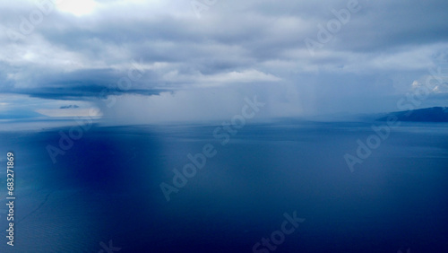 View from above of the rain in the distance. Aerial view of a rain cloud over the blue sea.