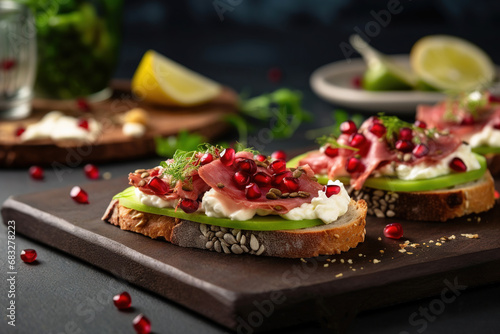 Canape  with toasted baguette   cheese  cucumber  pomegranate and salami on dark background