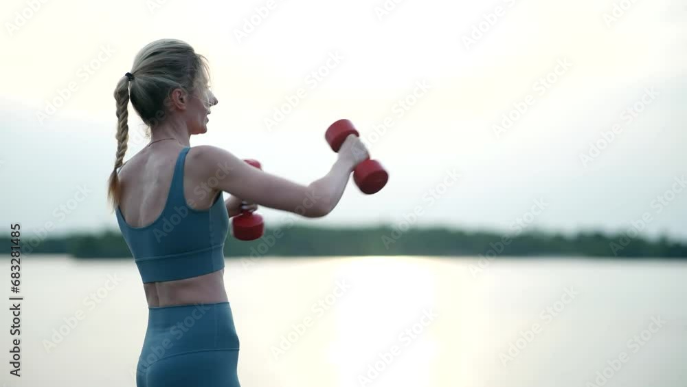Woman exercising with dumbbells . Outdoor pumping muscles practicing Woman exercising with dumbbells . Outdoor pumping muscles practicing