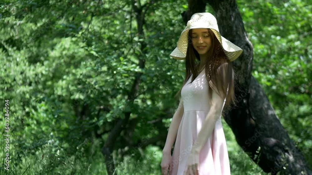 Beautiful girl posing in the garden. A young woman in a beautiful dress and hat walks in a summer green park.
Beautiful girl posing in the garden. A young woman in a beautiful dress and hat walks in a summer green park.