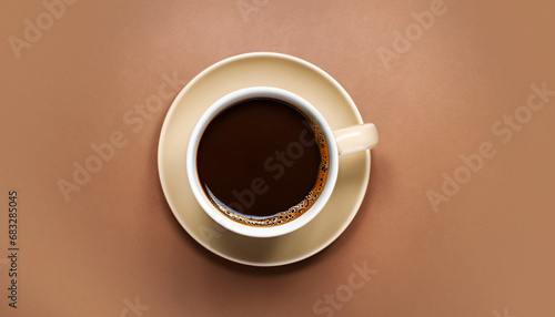 Cup of coffee on brown background, top view