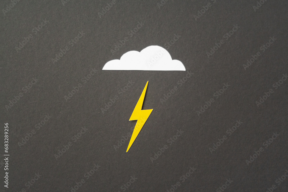 White cut out paper cloud and yellow lightning on black background ...