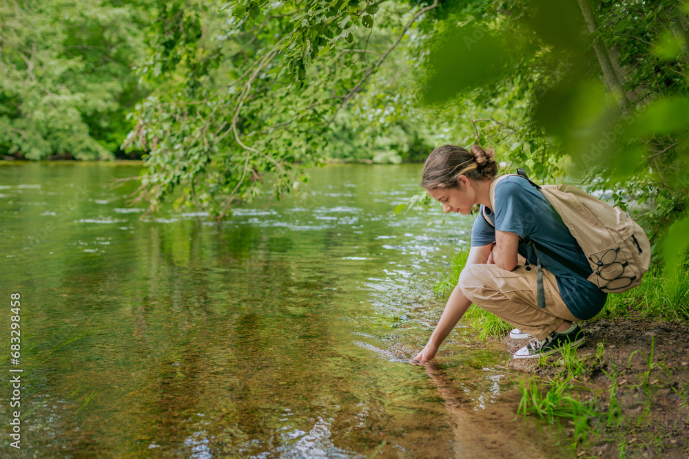 female tourist with a backpack resting on the river bank, enjoying nature, female tourist with a backpack resting on the river bank, enjoying nature,