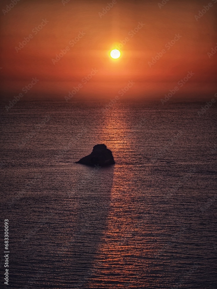 the lonly rock in the sea by the sunset - obrazy, fototapety, plakaty 
