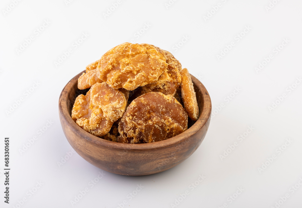 A close-up shot of jaggery neatly placed in a bowl against a clean white background A close-up shot of jaggery neatly placed in a bowl against a clean white background
