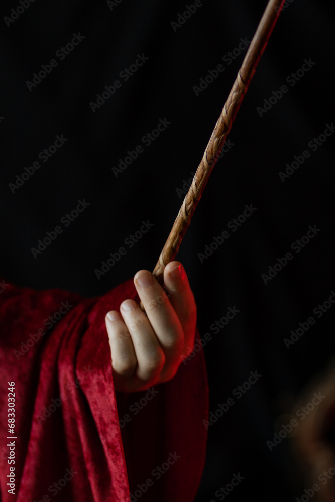 A magician's hand holds a carved magic wand A magician's hand holds a carved magic wand